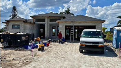 A white van is parked in front of a house under construction.
