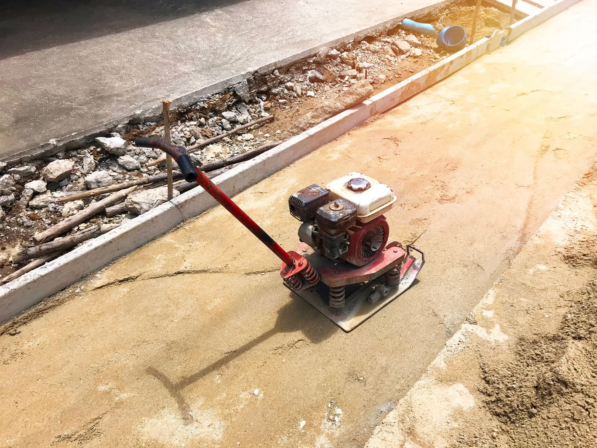 A red machine is sitting on the ground on a construction site