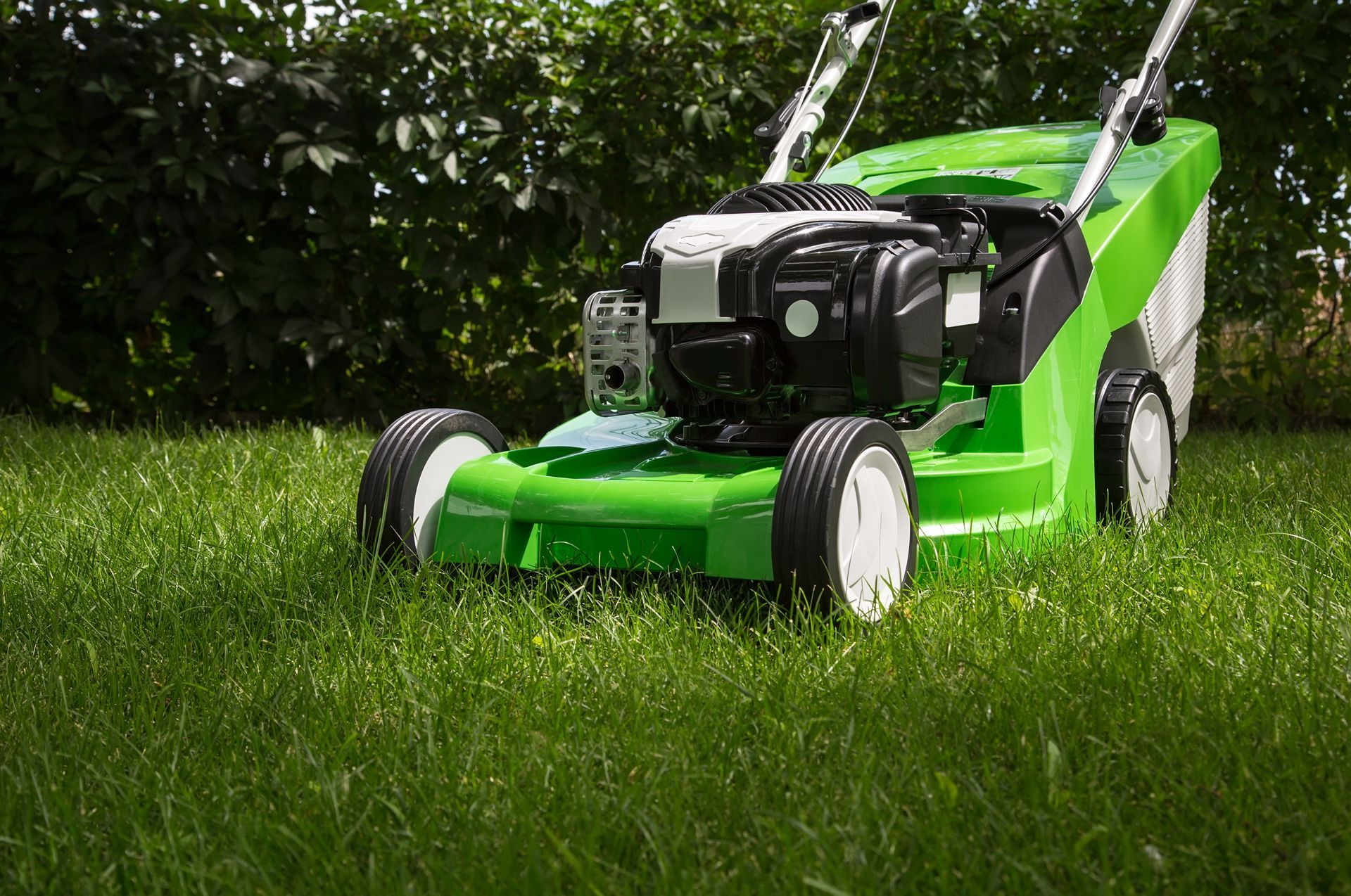 A green lawn mower is sitting on top of a lush green lawn