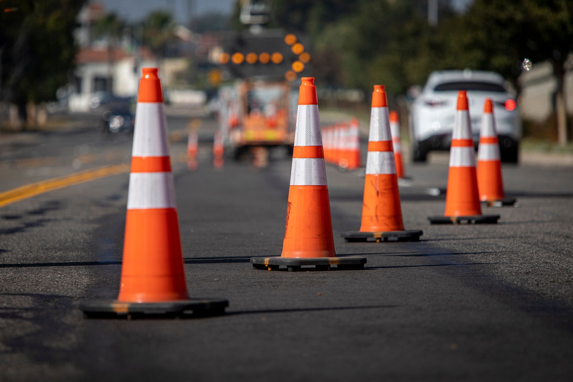 A row of orange and white traffic cones on the side of a road