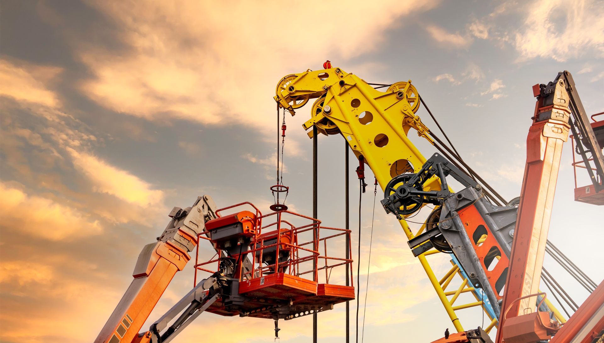 A couple of cranes are sitting next to each other in front of a cloudy sky