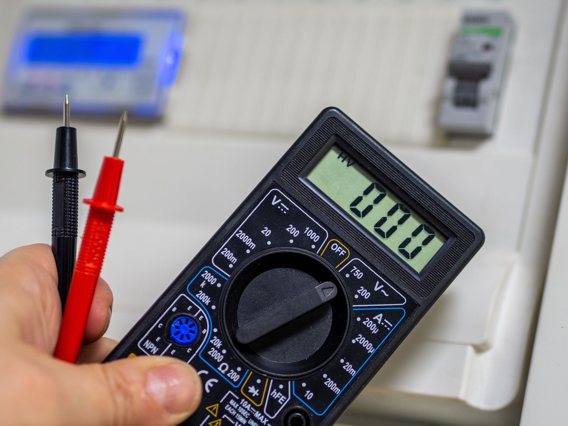 A person is holding a digital multimeter in their hand