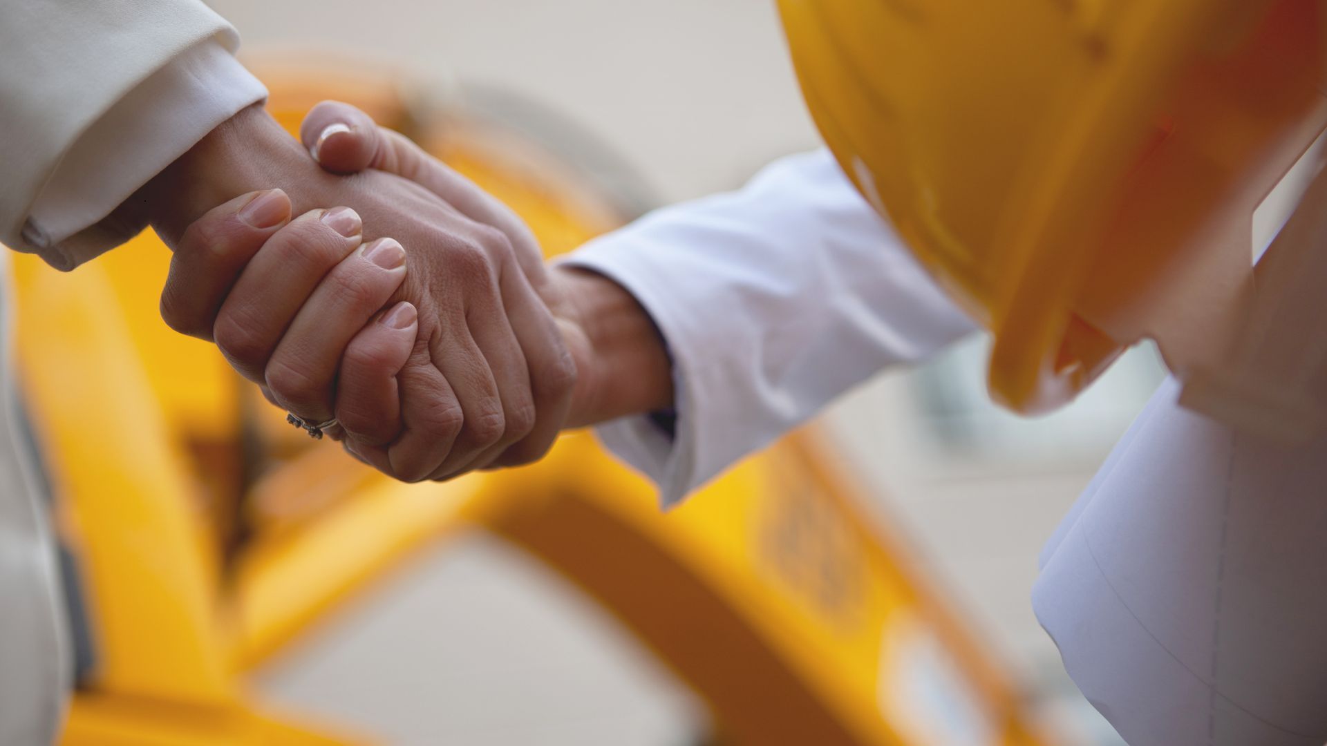A man wearing a hard hat is shaking hands with another man.