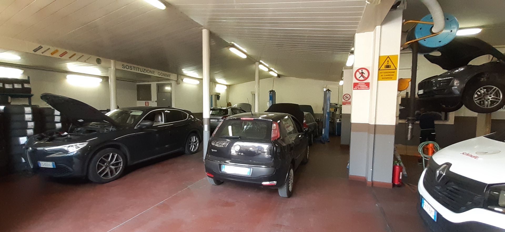 Una fila di auto sono parcheggiate in un garage con i cofani aperti.