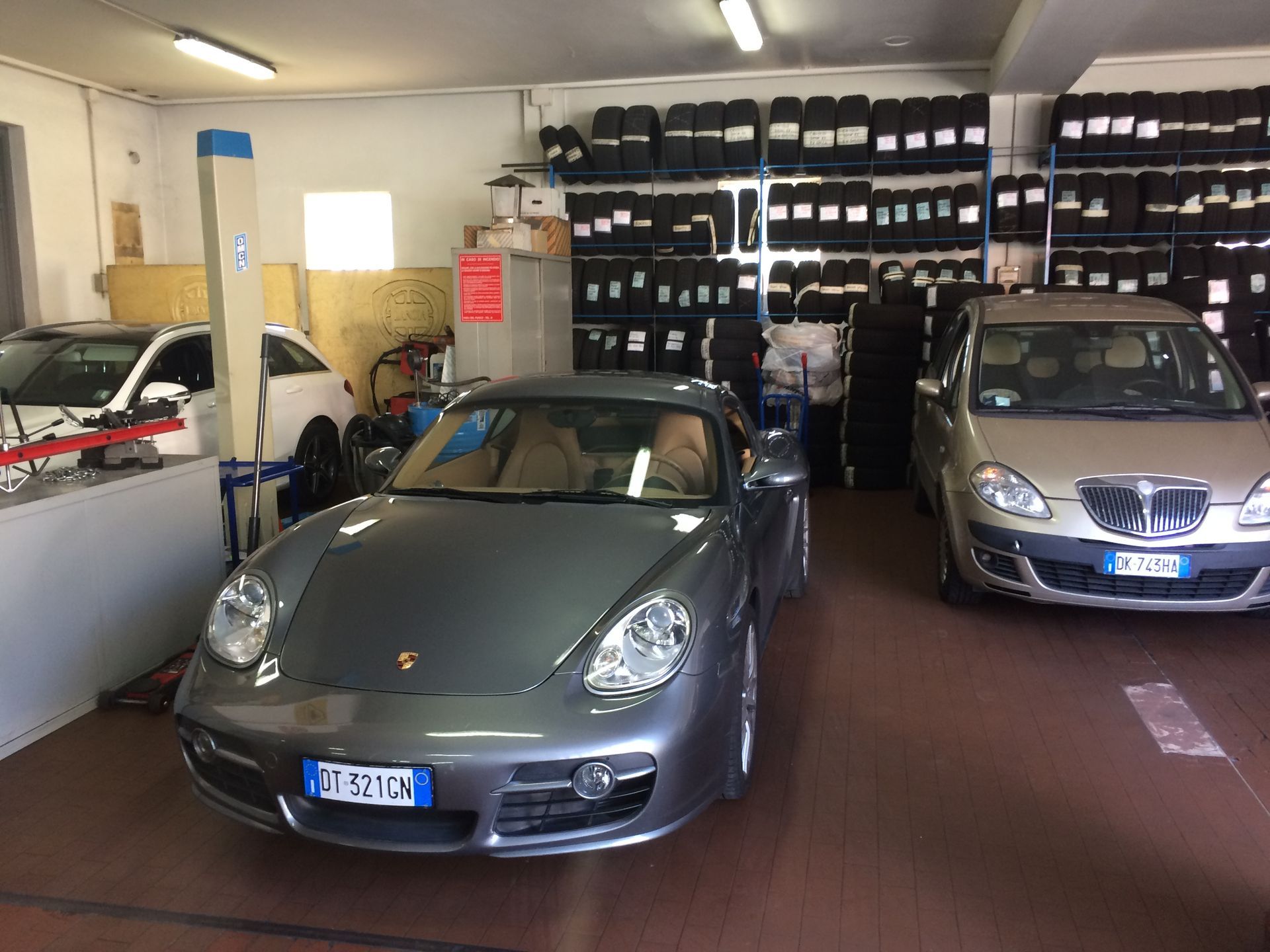 Una porsche grigia è parcheggiata in un garage insieme ad altre auto.