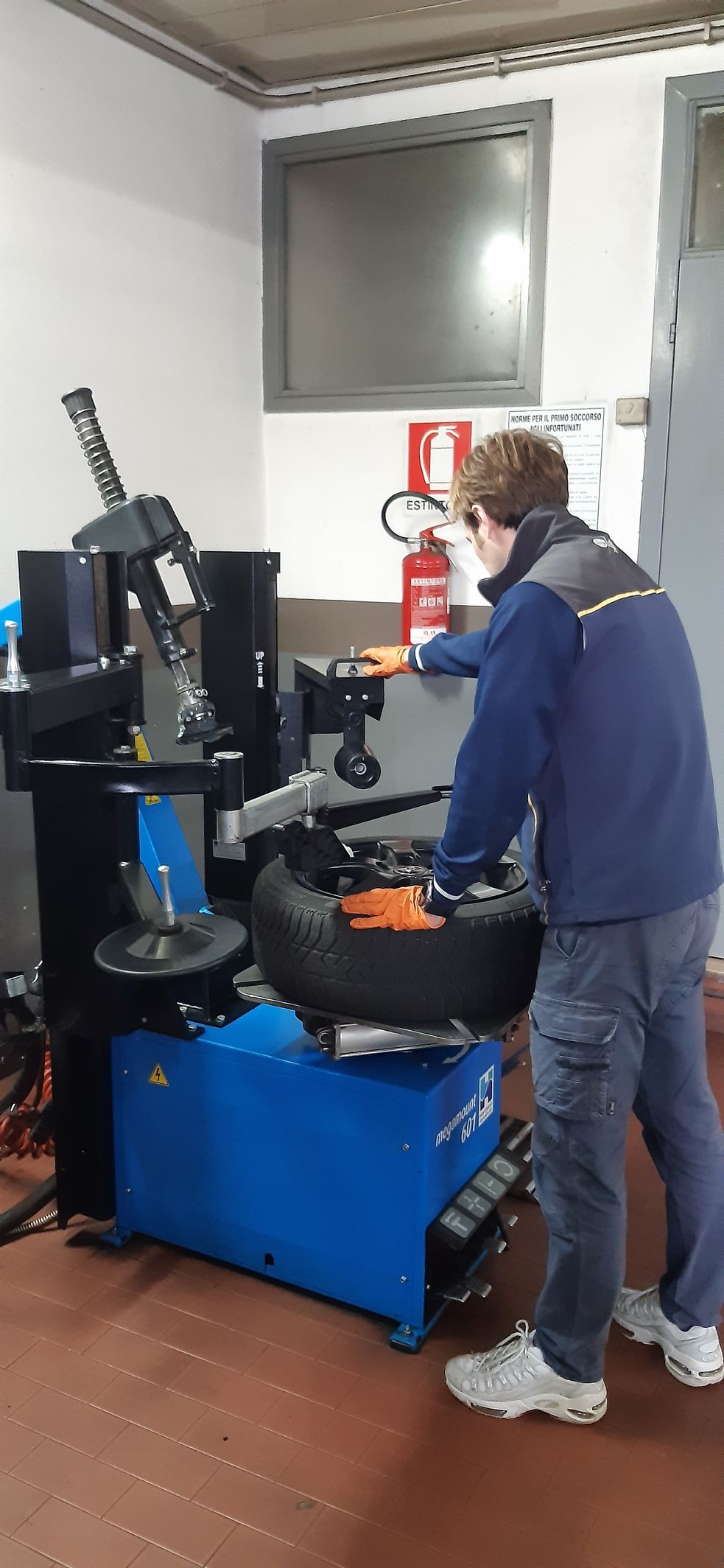 Un uomo sta cambiando una gomma su un macchinario in un garage.