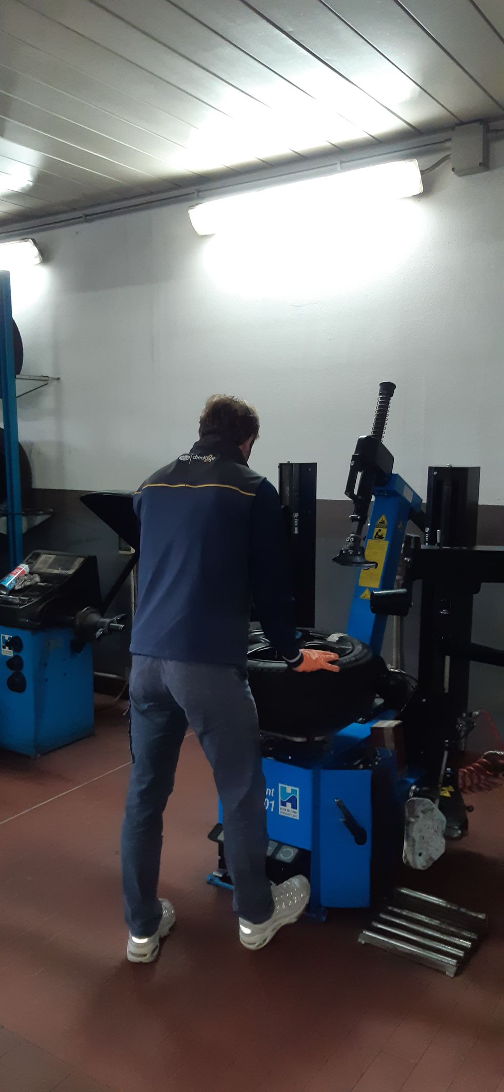 Un uomo sta lavorando su una macchina equilibratrice per pneumatici in un garage.