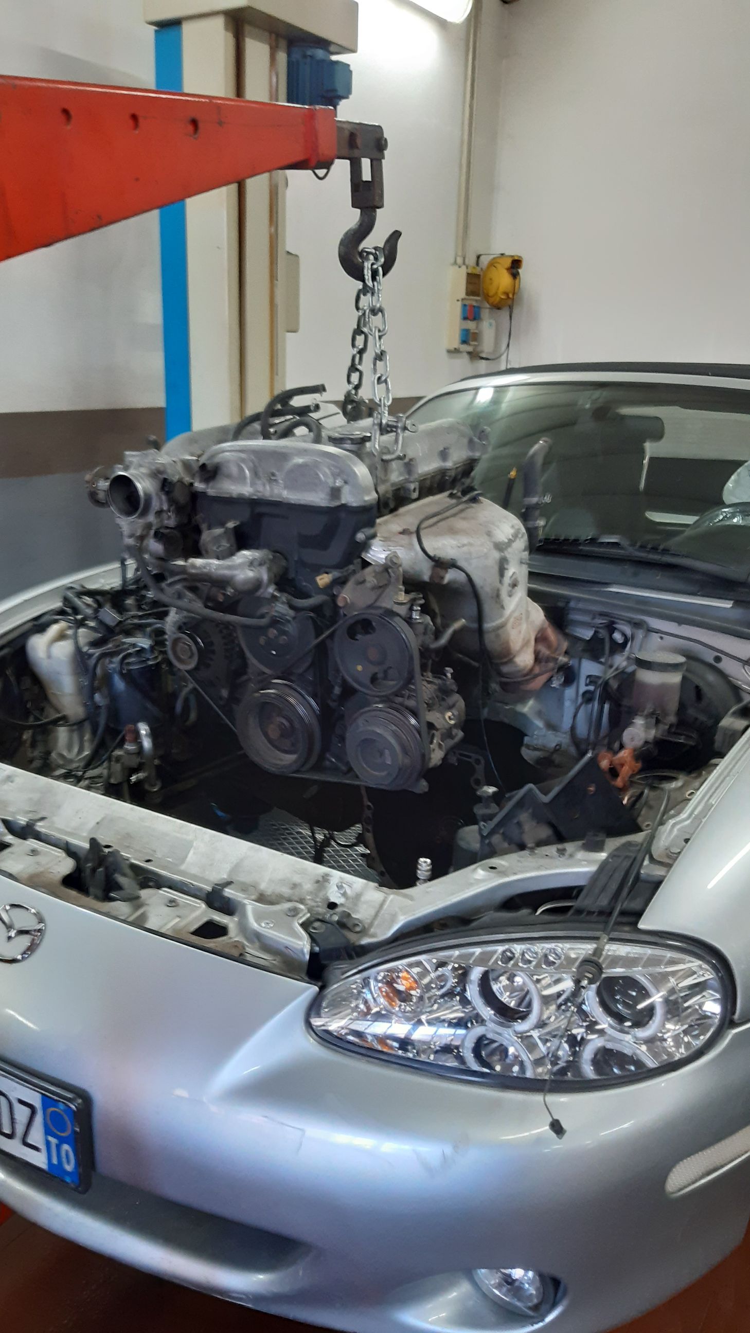 Il motore di un'auto viene sollevato da una gru.