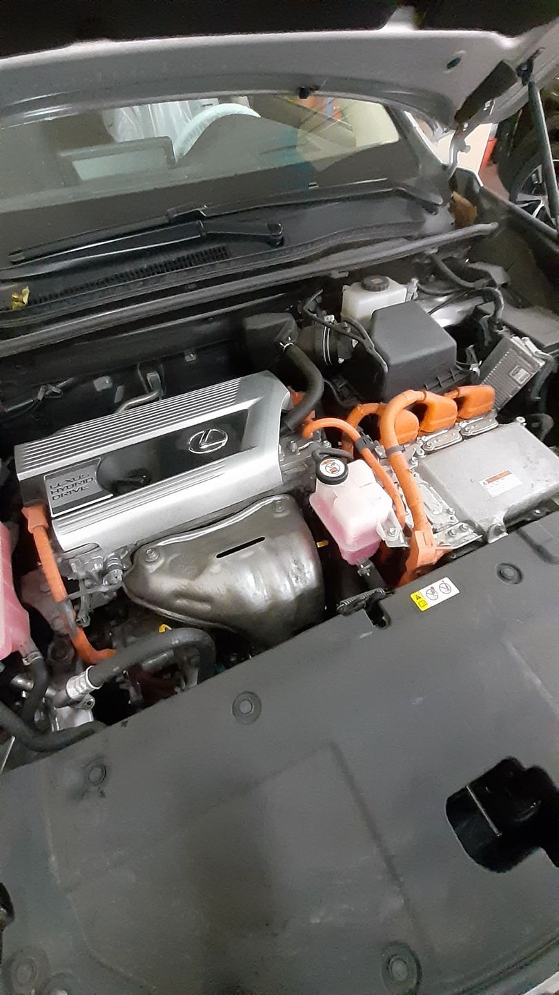 Un primo piano del motore di un'auto con il cofano aperto.