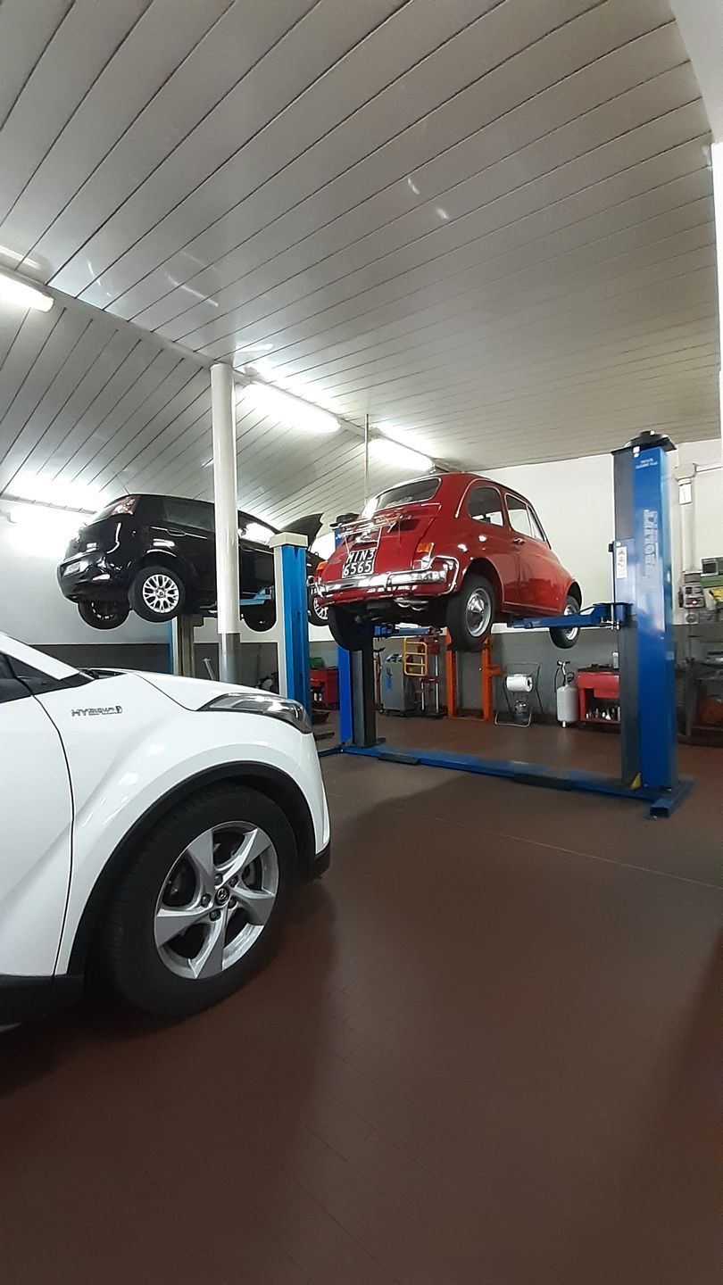 Un'auto rossa è parcheggiata su un ponte elevatore in un garage.