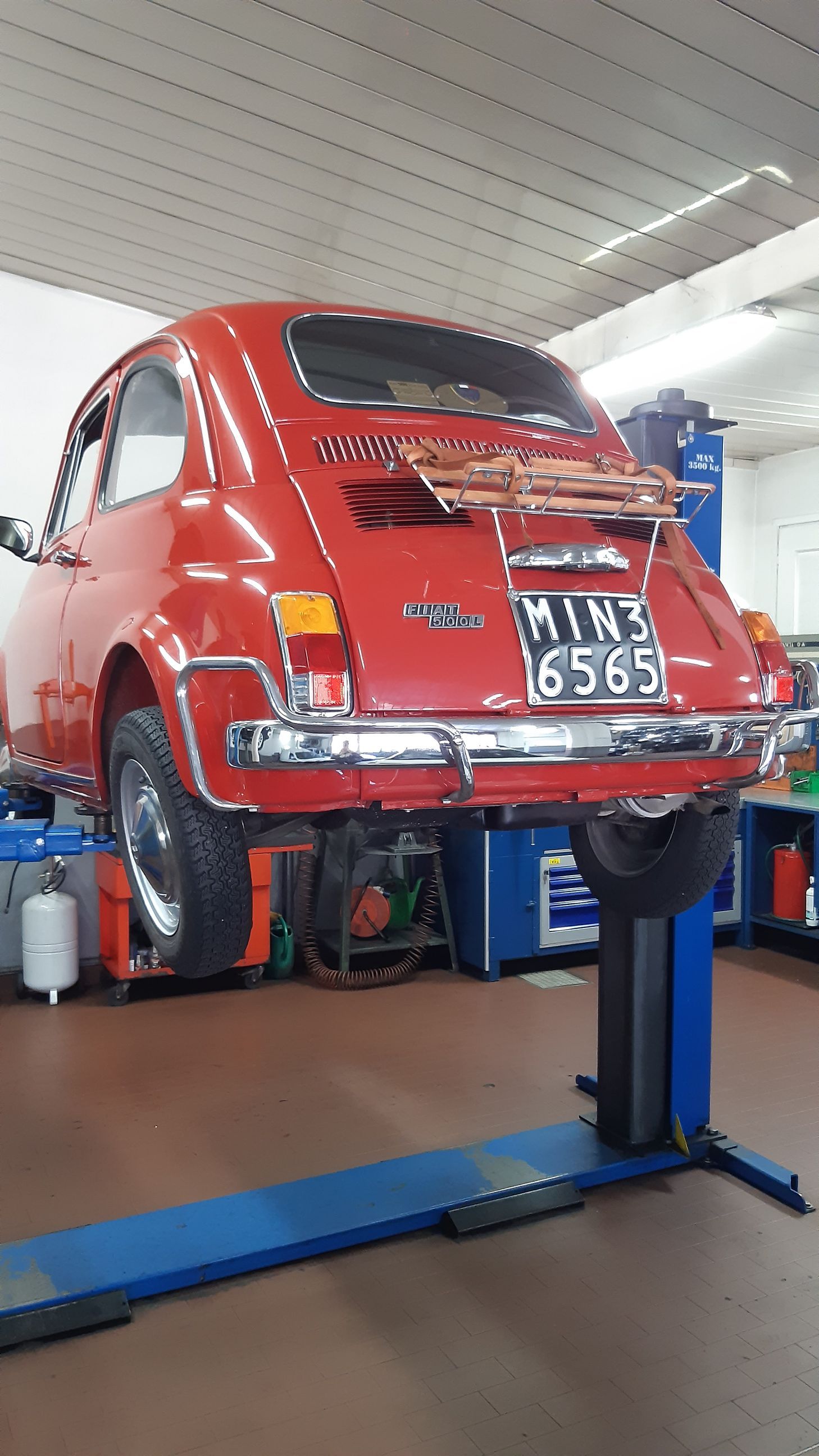 Un'auto rossa è parcheggiata su un ponte elevatore in un garage.
