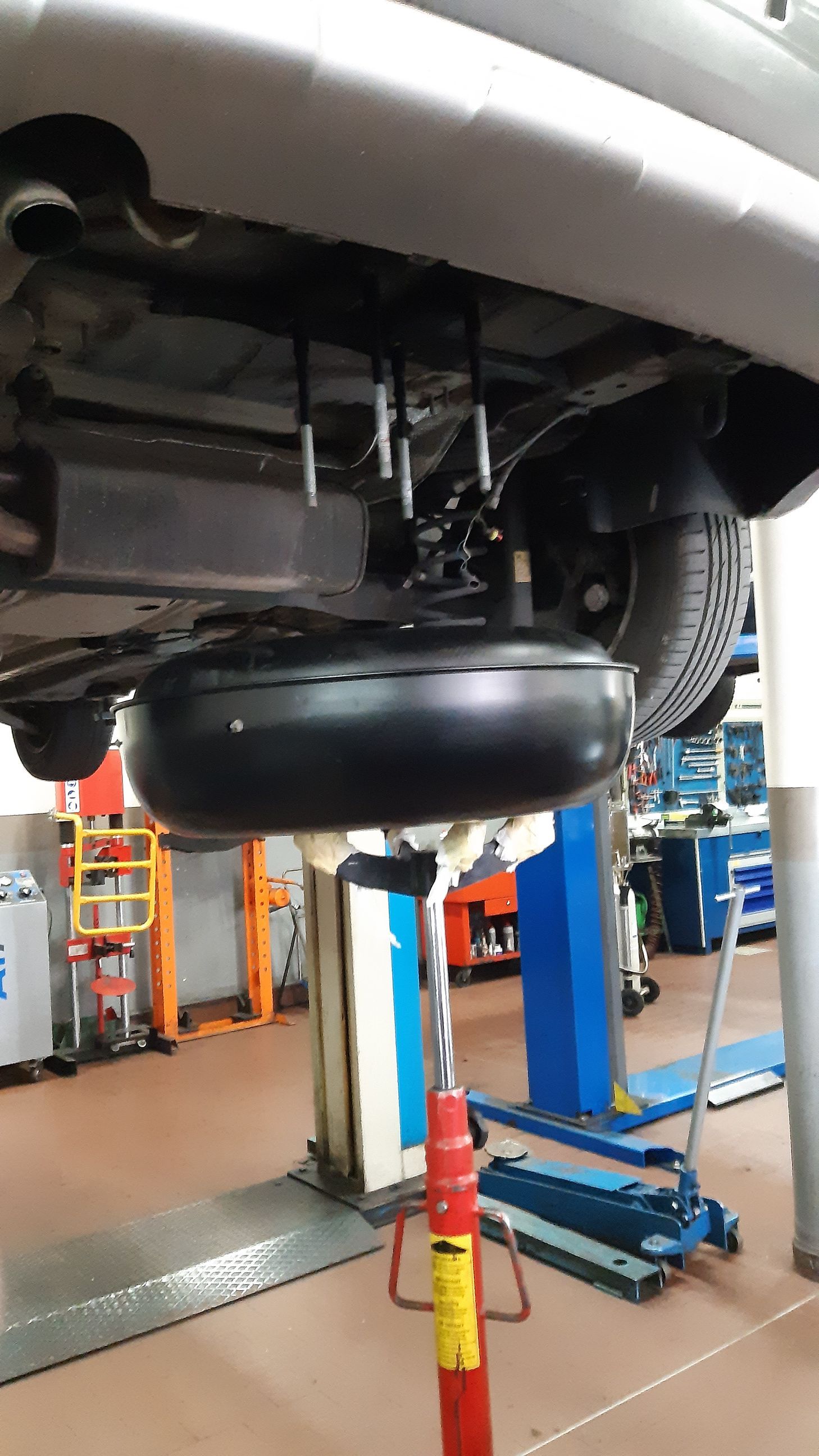 Un'auto è parcheggiata su un ponte sollevatore in un garage.