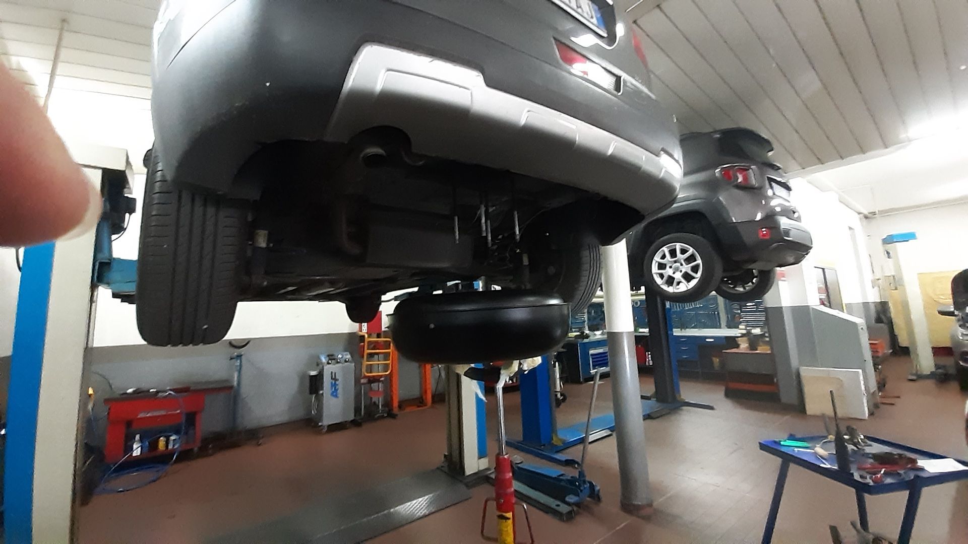 Un'auto è parcheggiata su un ponte sollevatore in un garage.