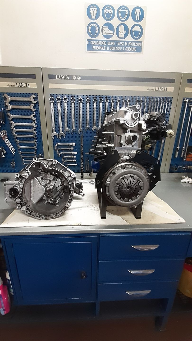 Un motore e un cambio sono appoggiati su un tavolo in un garage.
