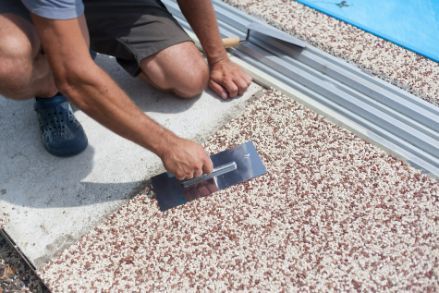 Concreters finishing a concreting project by applying exposed aggregate to a residential pool side in Bendigo VIC.