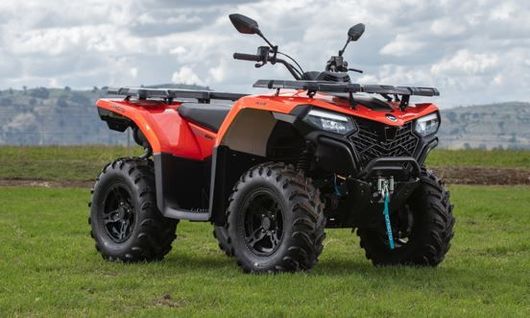 A red atv is parked in a grassy field.