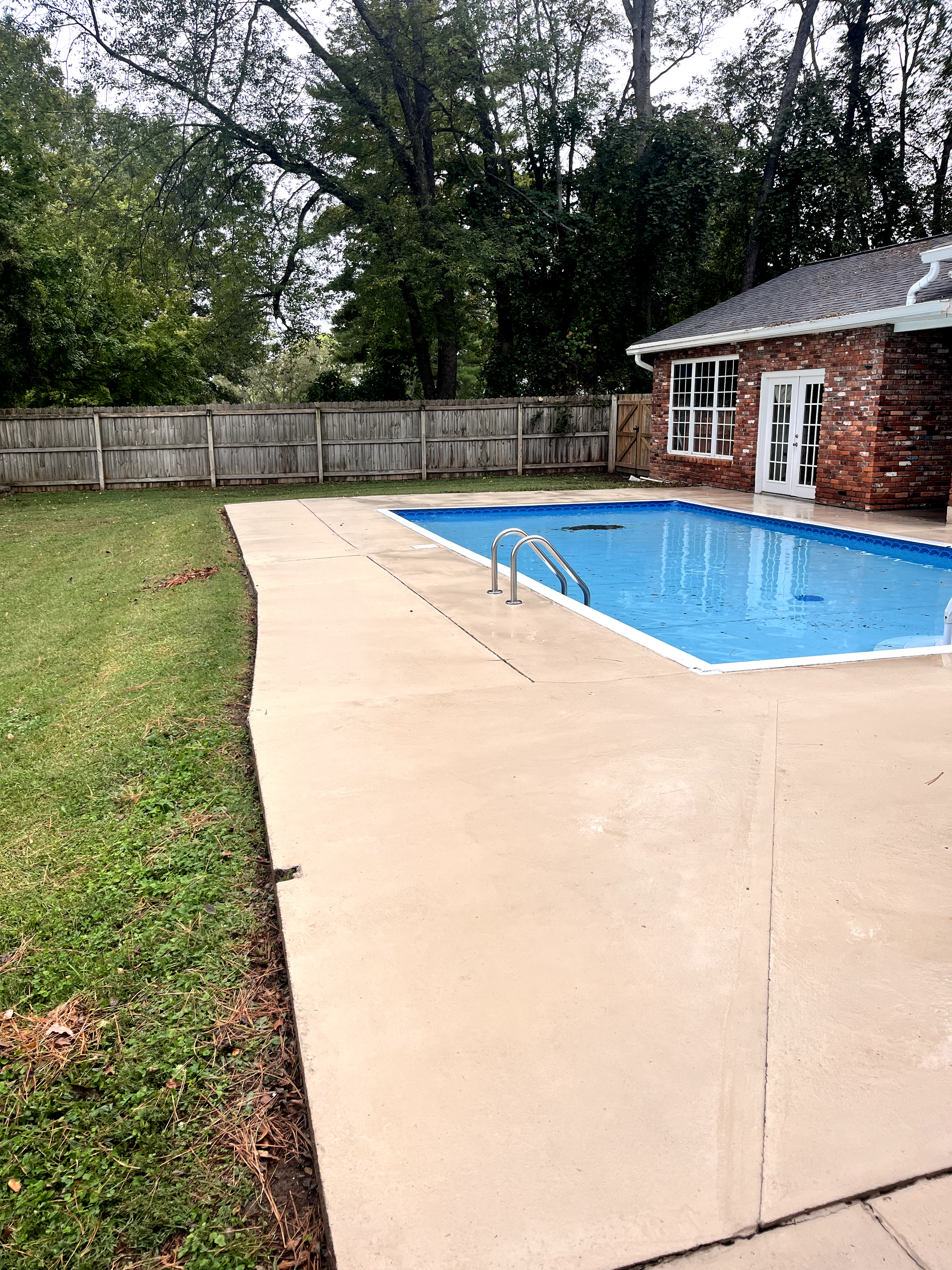There is a large swimming pool in the backyard of a house.