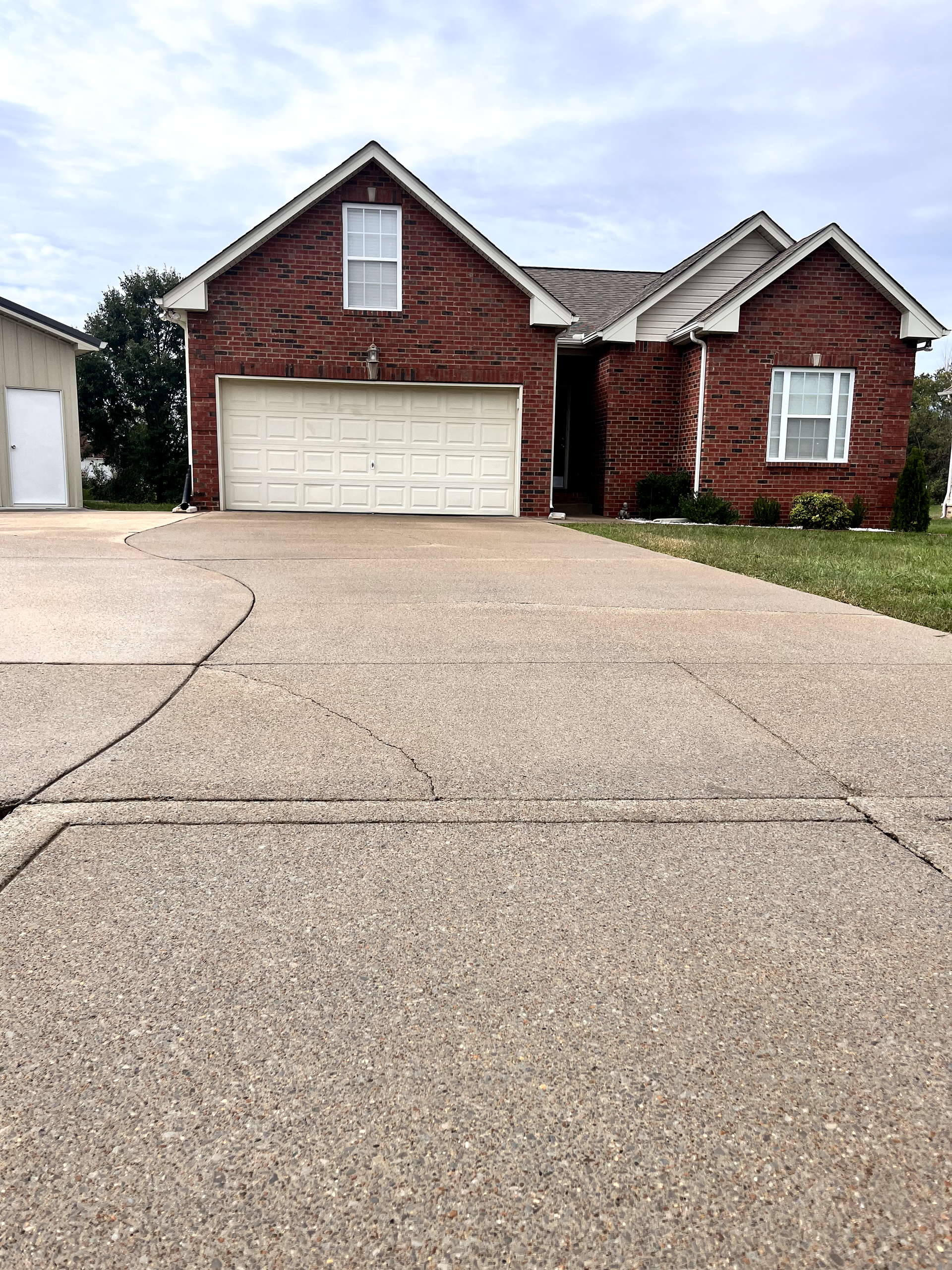 A brick house with two garage doors and a driveway in front of it.