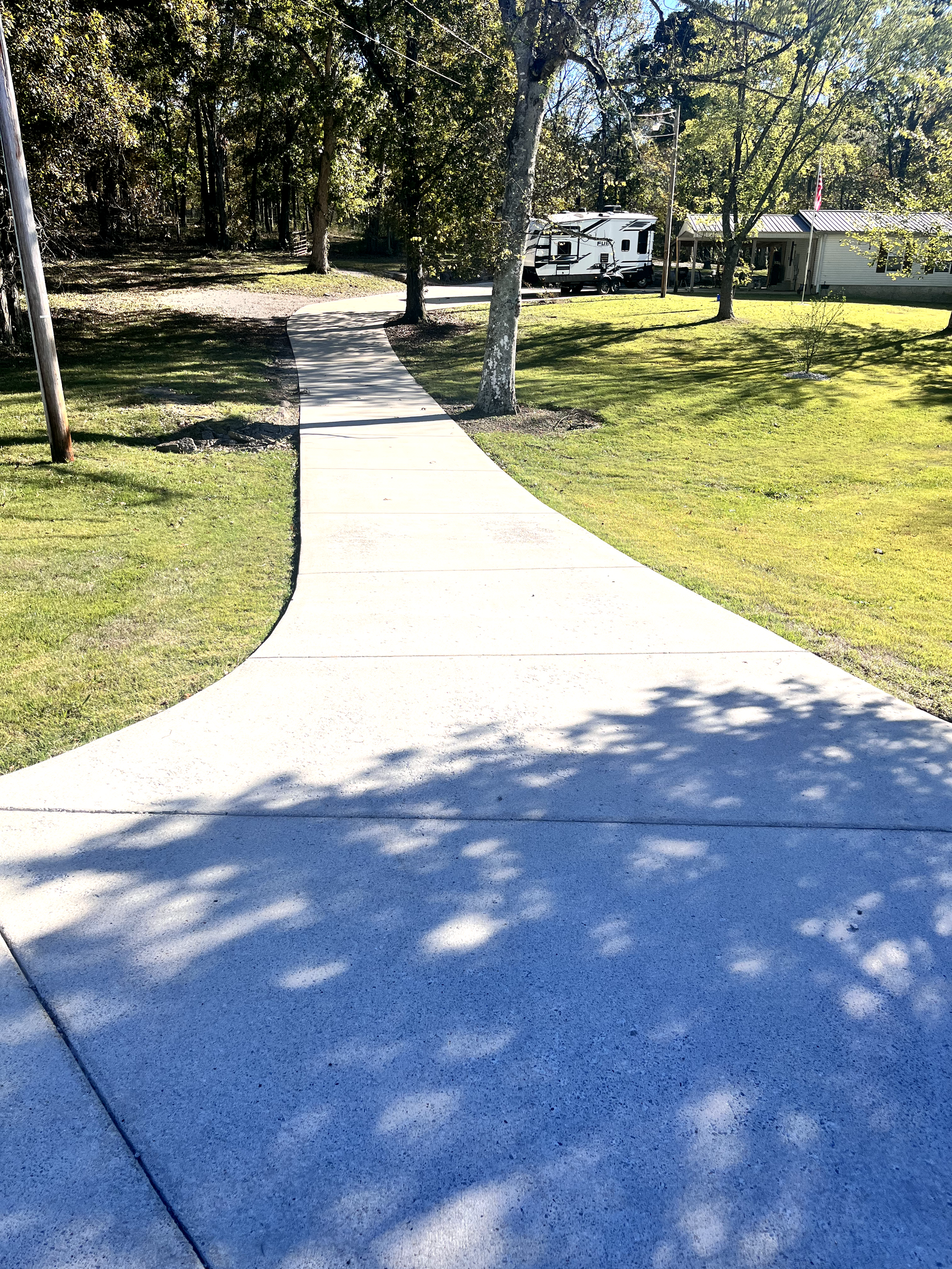 A concrete walkway leading to a house in a park.