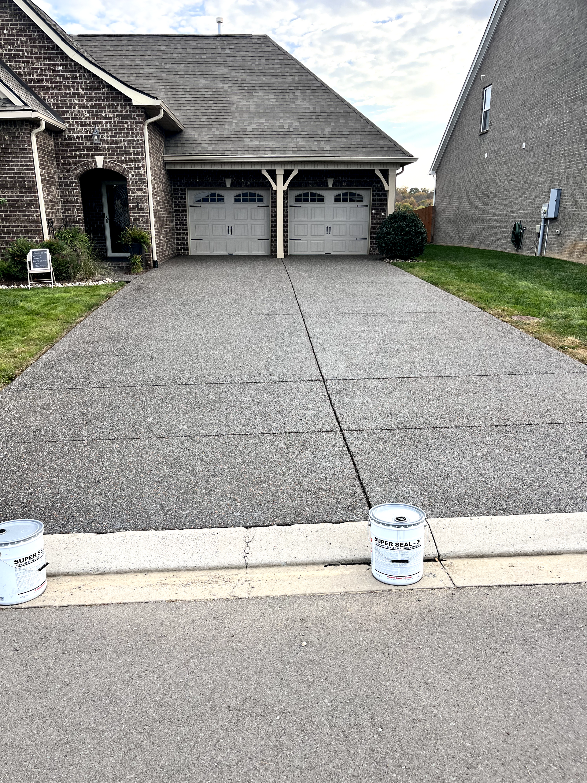 A driveway leading to a house with two garage doors.