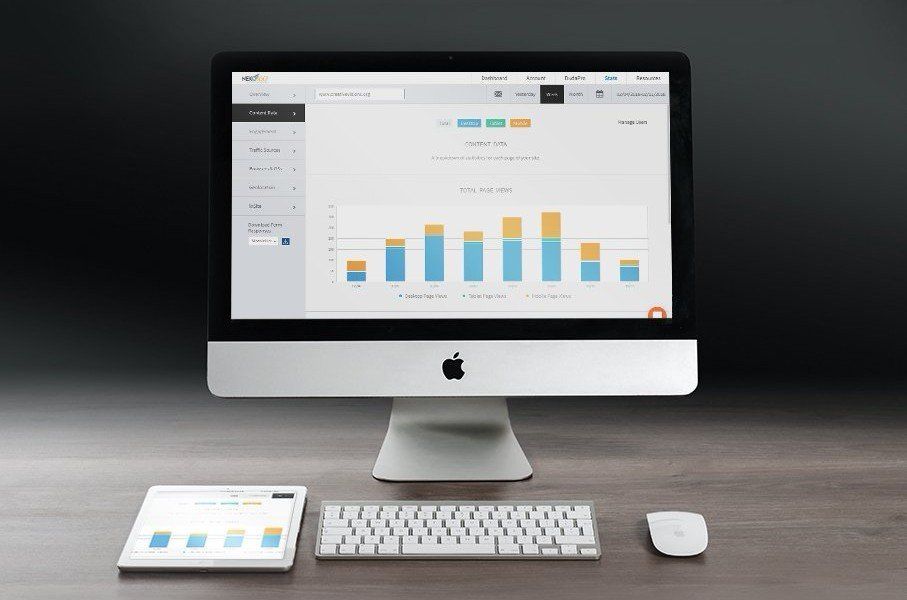 A monitor with a tablet next to it both showing a gray and blue bar chart