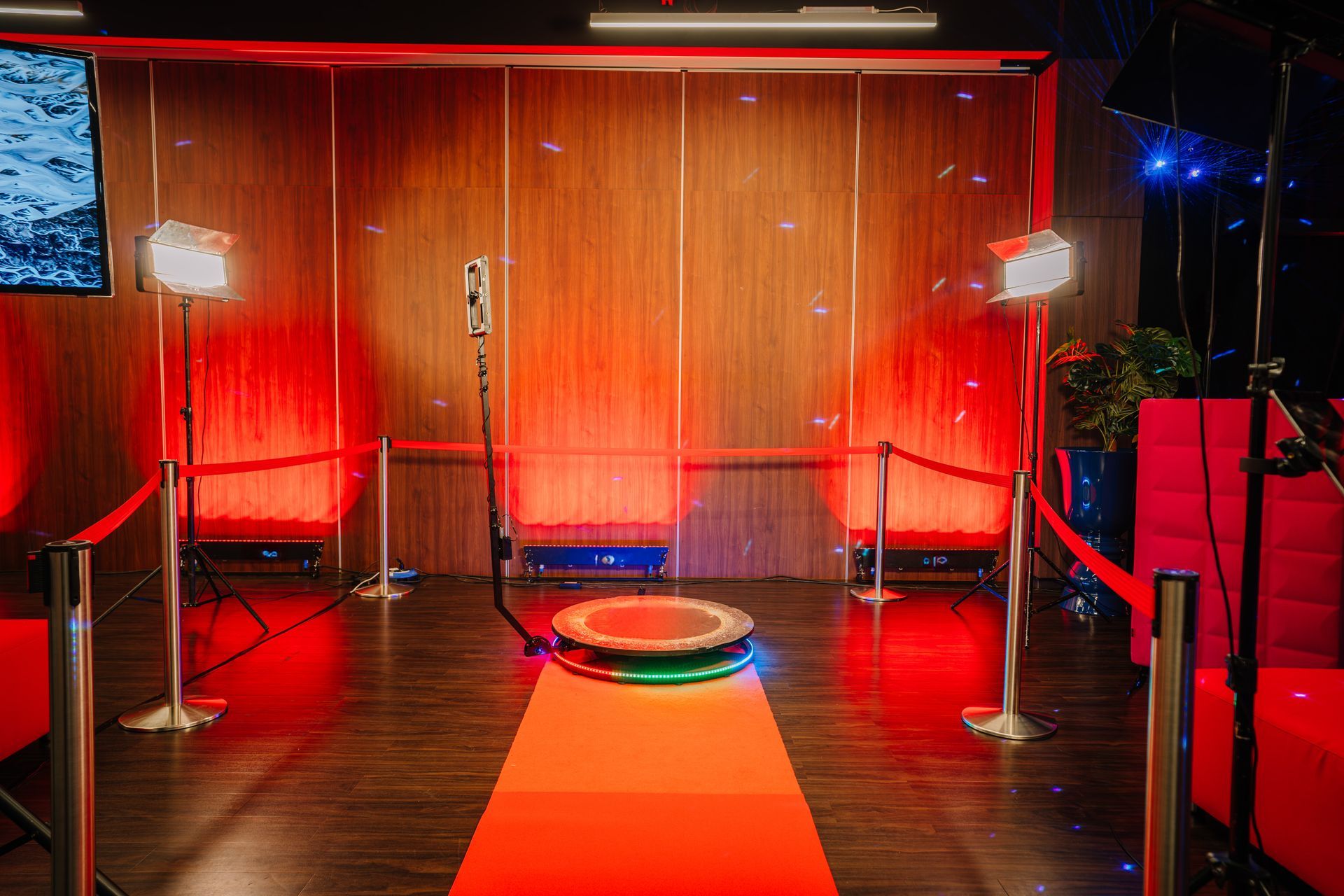 Photo booth setup with red carpet, lights, and a rotating platform.