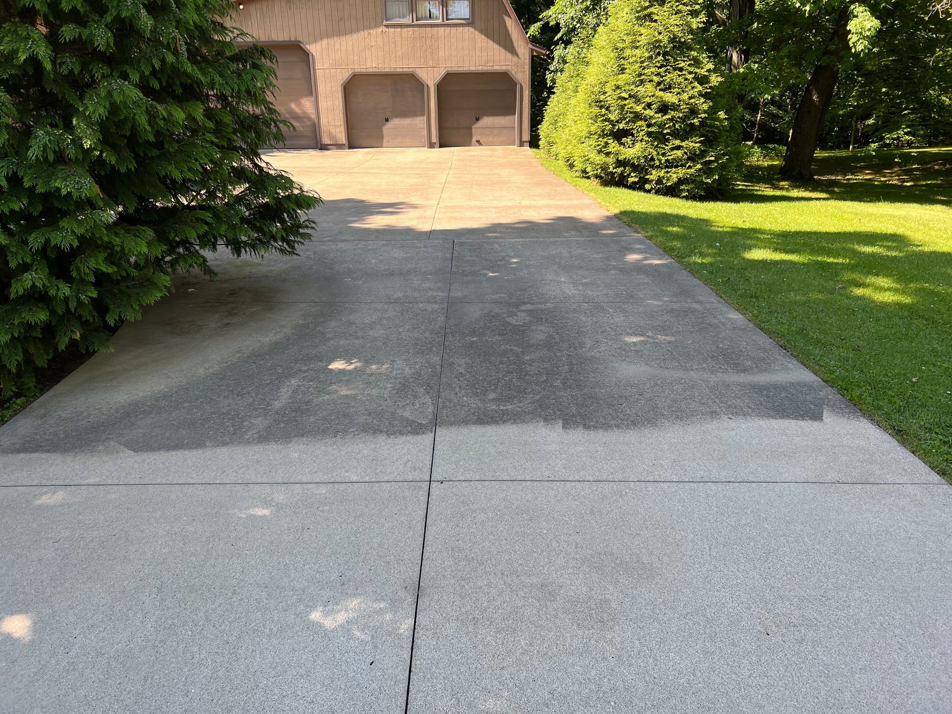 A concrete driveway leading to a house with two garages.