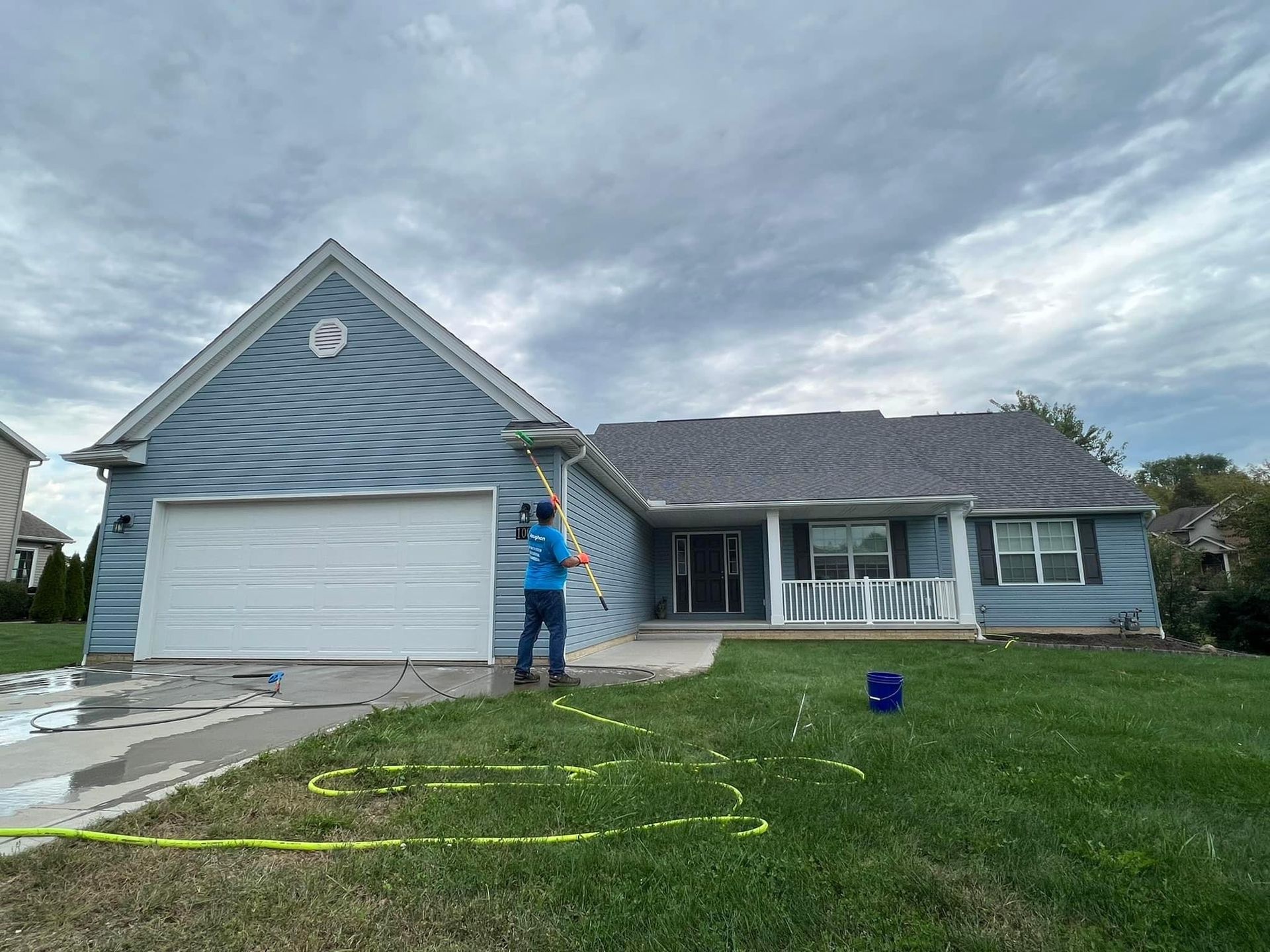A man is cleaning the side of a house with a hose.