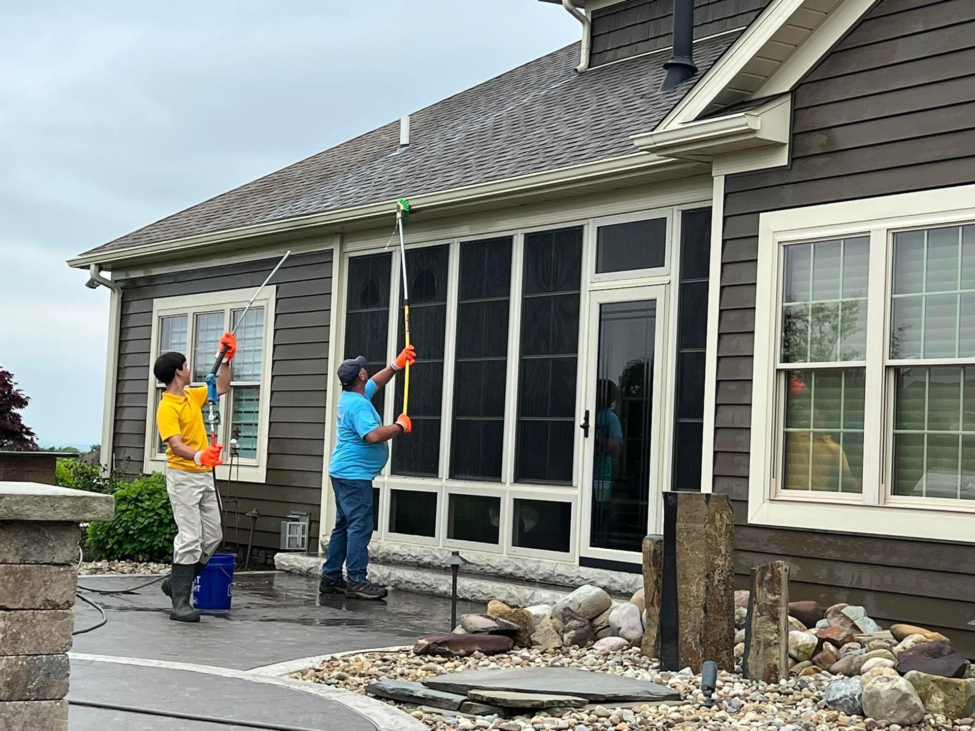 Two men are cleaning the windows of a house.