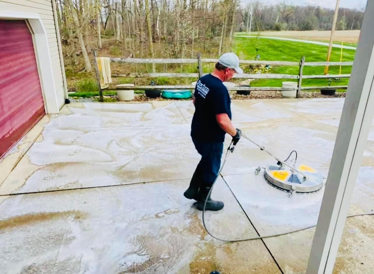 A man is cleaning a driveway with a machine.