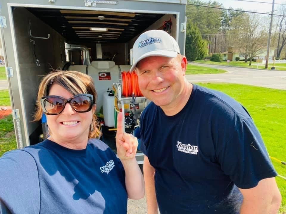 A man and a woman are standing next to each other in front of a trailer.