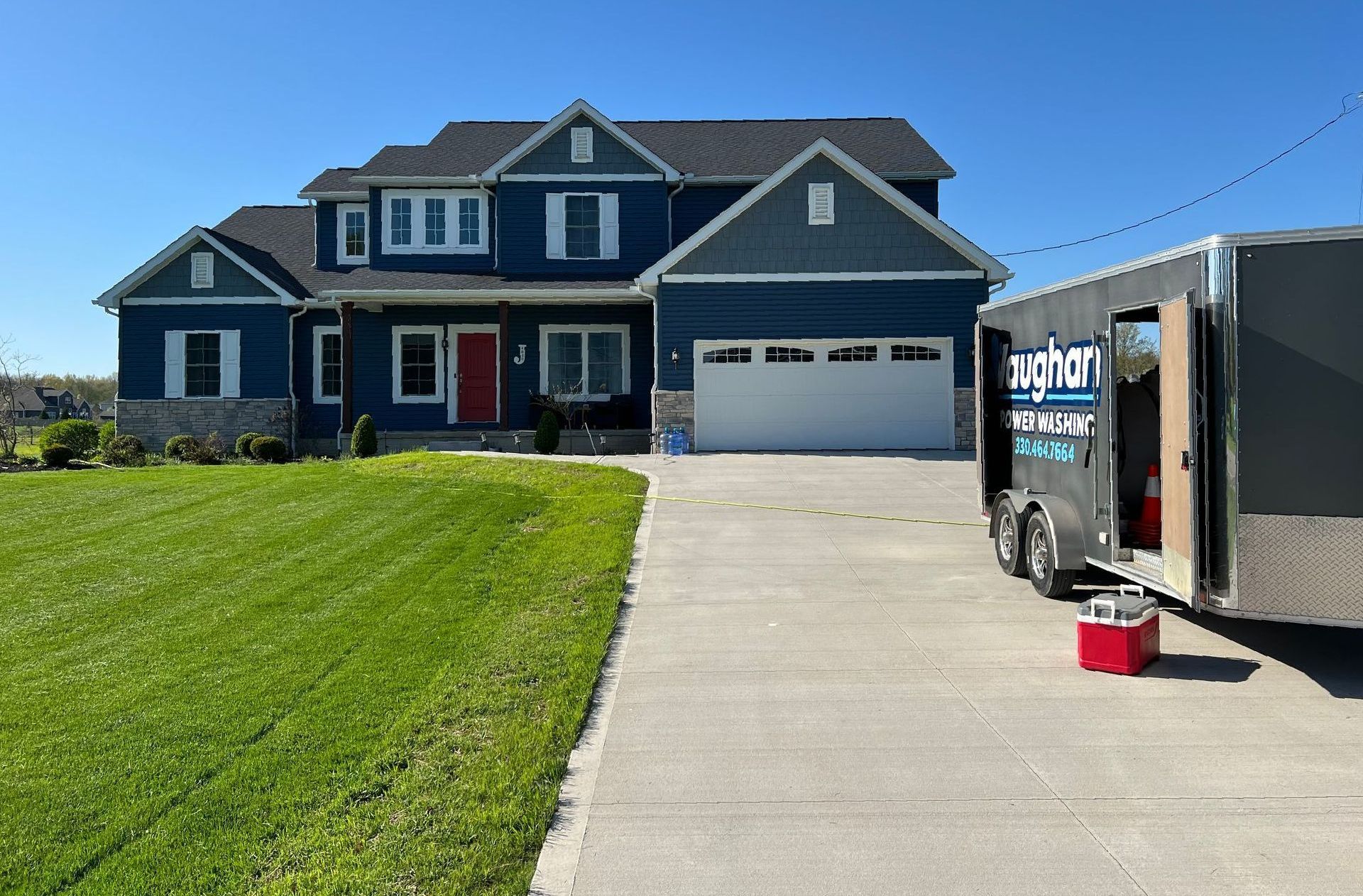 A large blue house with a trailer parked in front of it.