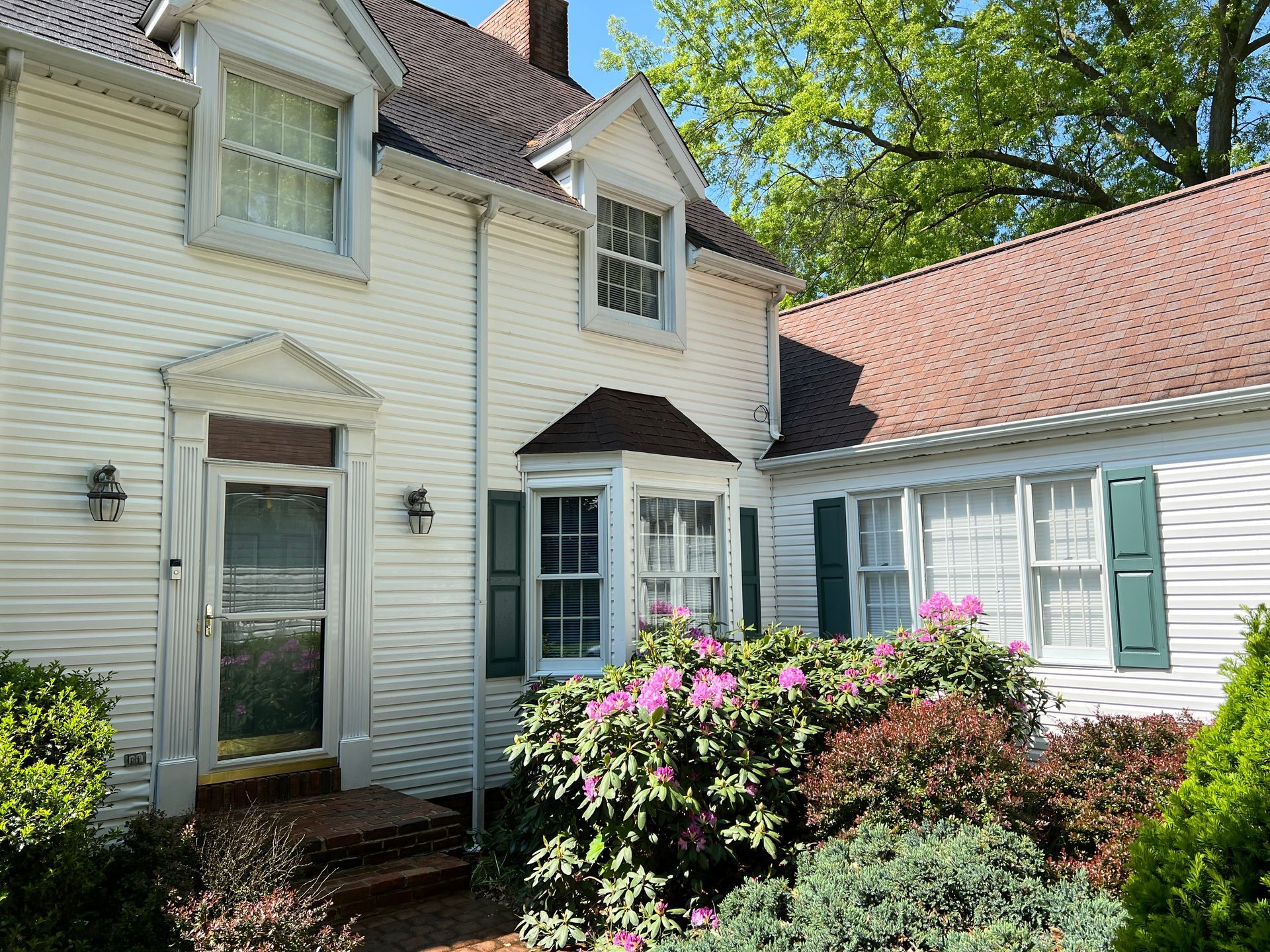 A white house with a red roof and green shutters
