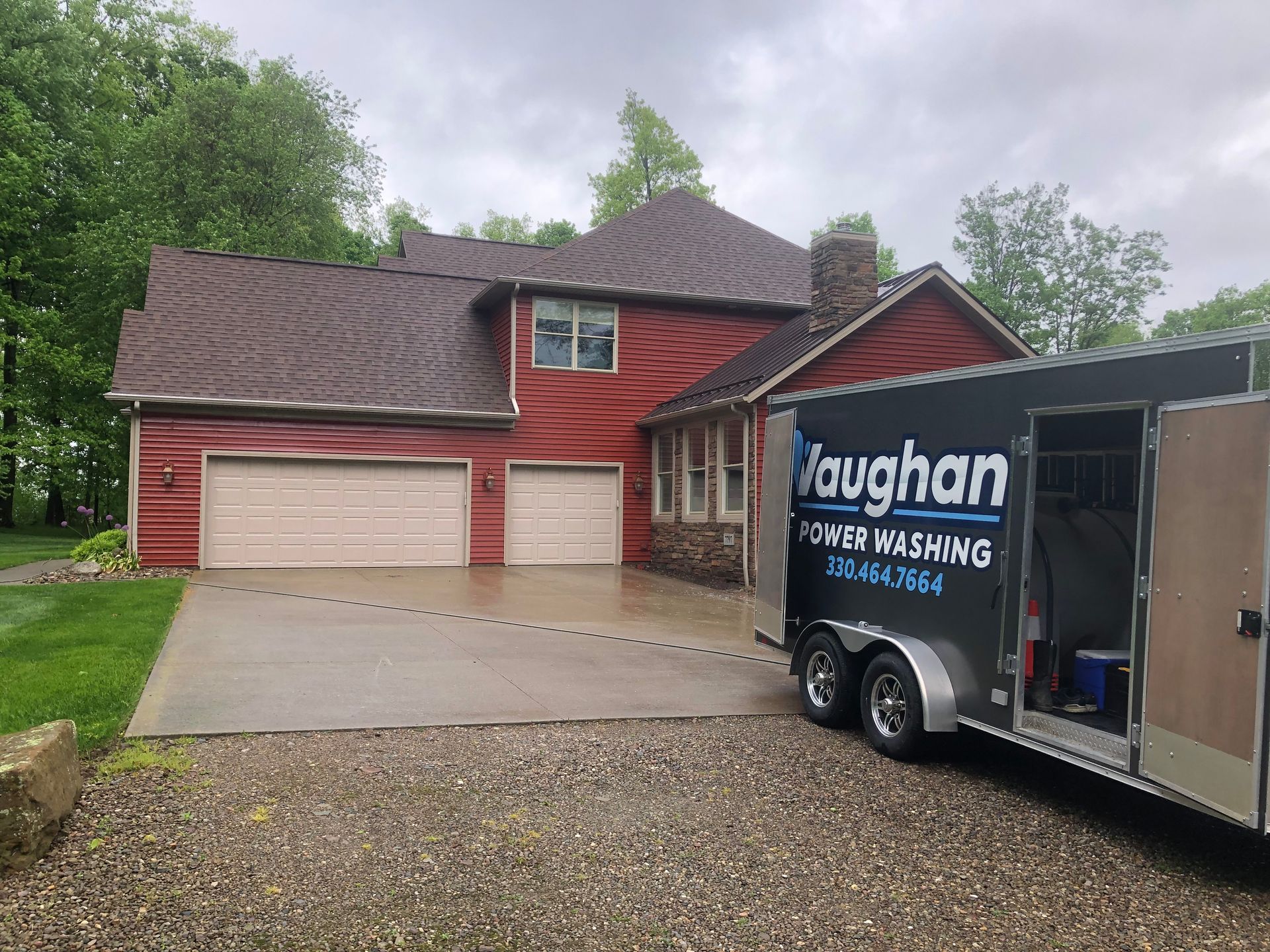 A trailer is parked in front of a large red house.