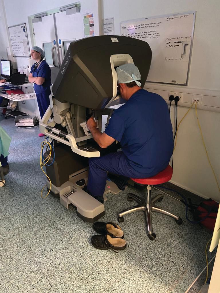 A man is sitting on a red stool in front of a machine.