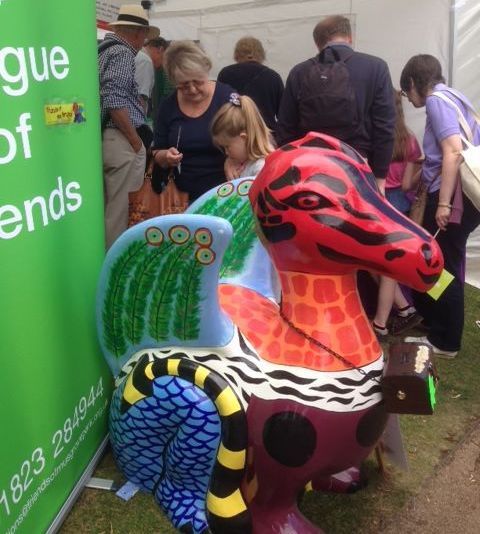 A group of people standing around a statue of a dragon.