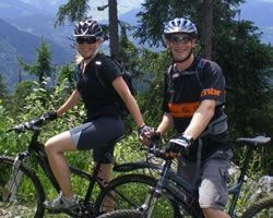 A man and a woman are riding bicycles in the mountains in fundraising cycle.
