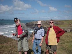 Three men are standing on top of a hill near the ocean in charity walk.