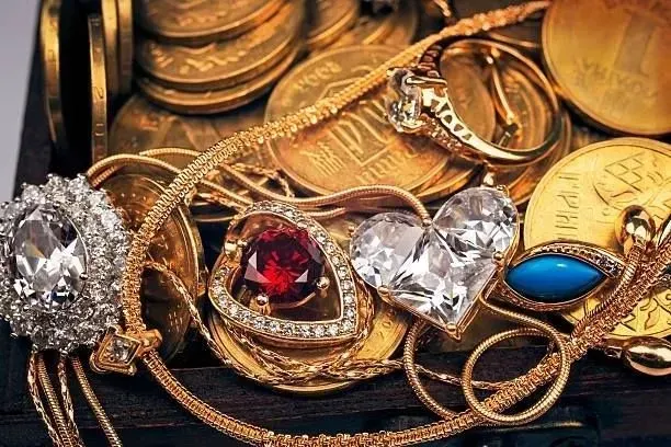 A bunch of gold jewelry is sitting on top of a pile of gold coins.