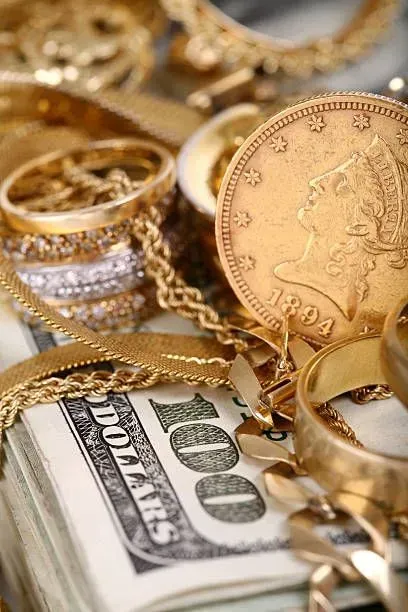 A pile of gold jewelry is sitting on top of a stack of 100 dollar bills.