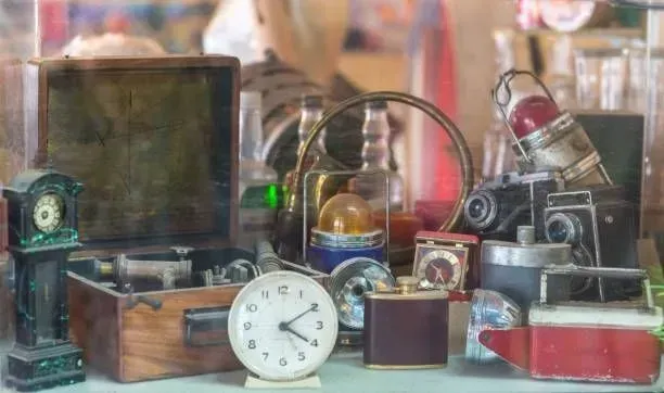 A clock is sitting on a table surrounded by other antique items.