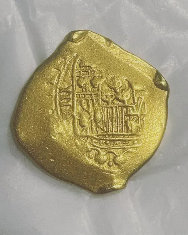 A close up of a gold coin on a white surface