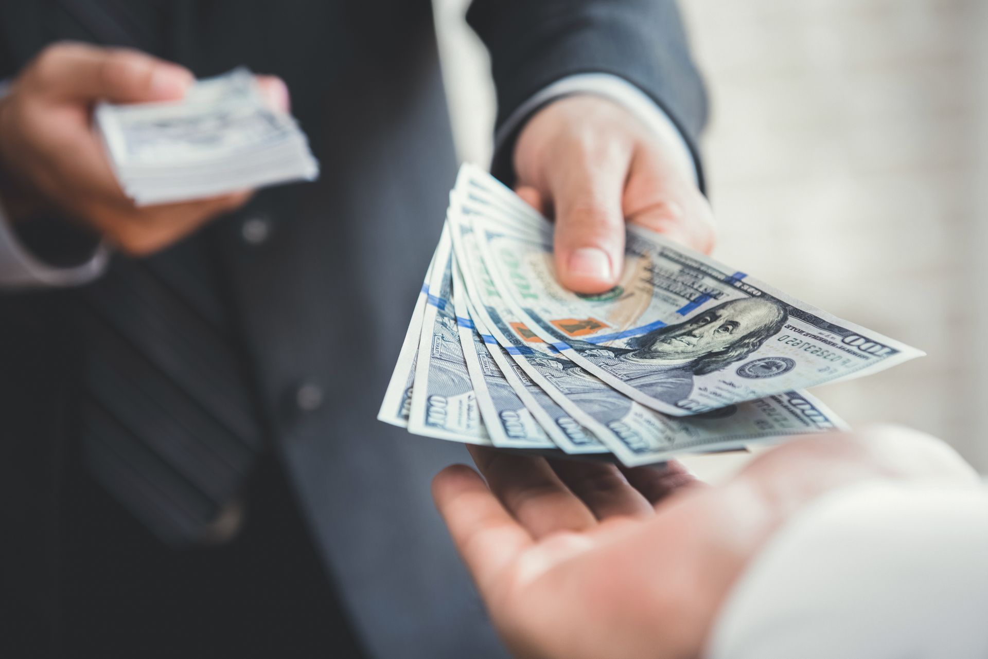 Close-up of a loaner giving cash to another man for a personal loan.