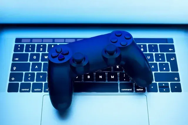 A video game controller is sitting on top of a laptop keyboard