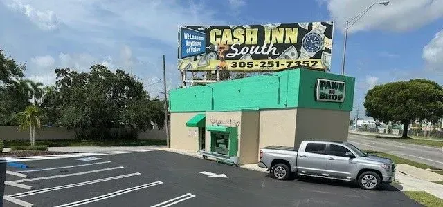A silver truck is parked in front of a cash inn south building.