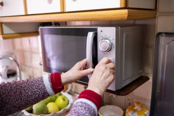 A person is opening a microwave oven in a kitchen.