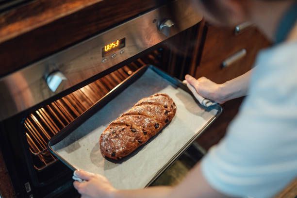 A person is taking a loaf of bread out of the oven.