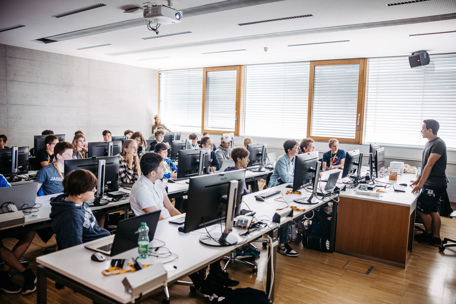 Eine Gruppe von Kindern sitzt an Schreibtischen in einem Klassenzimmer mit Computern.