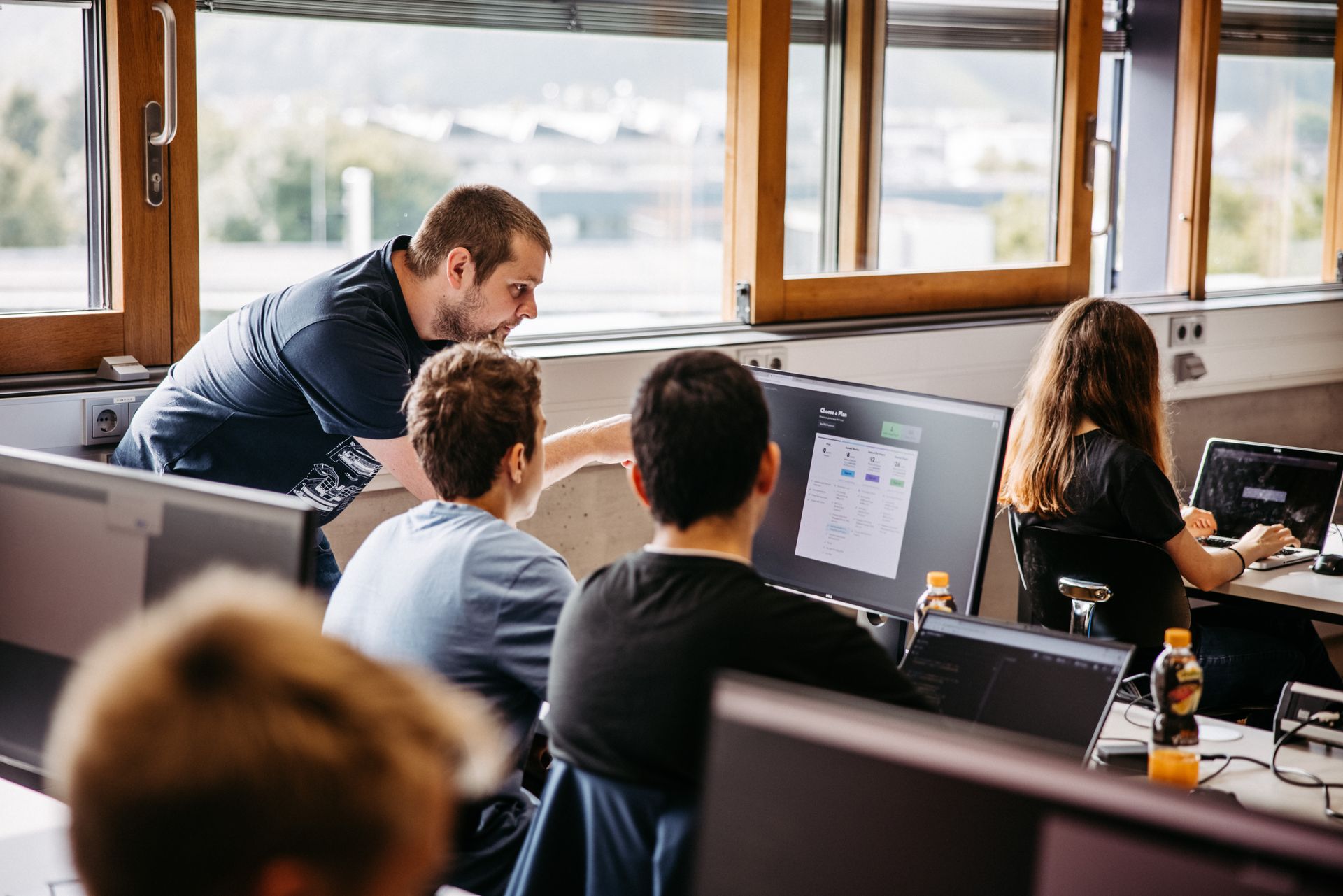 Eine Gruppe von Kindern sitzt in einem Klassenzimmer vor Computerbildschirmen.