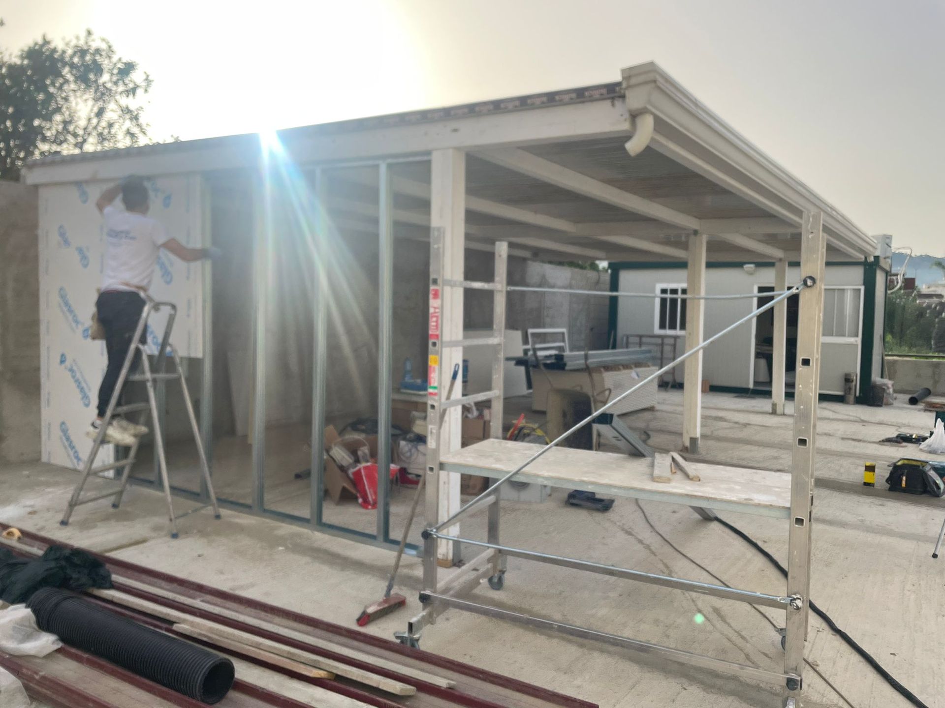 Un operaio edile installa pannelli su un edificio. Sono visibili la struttura in acciaio, le impalcature e le pareti in cemento.